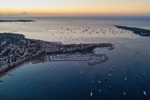 Aerial view of the port of Cannes with yachts and boats anchored in the bay surrounded by coastal city architecture and calm sea at sunset in Cannes Provence Alpes Cote d Azur France. Aerial view of the port of Cannes with yachts and boats anchored in the bay surrounded by coastal city architecture and calm sea at sunset in Cannes Provence Alpes Cote d Azur France.