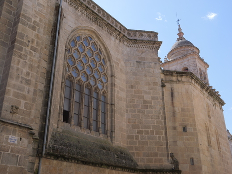 View of the stone facade and ornate gothic window of the Catedral de Ourense under a clear blue sky in Ourense Ourense Spain. View of the stone facade and ornate gothic window of the Catedral de Ourense under a clear blue sky in Ourense Ourense Spain.