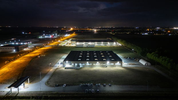 Aerial view of an illuminated industrial warehouse facility at night with a parking lot and surrounding fields in Sremska Mitrovica Vojvodina Serbia. Aerial view of an illuminated industrial warehouse facility at night with a parking lot and surrounding fields in Sremska Mitrovica Vojvodina Serbia.