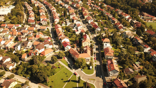 Aerial view of a residential neighborhood featuring houses with red tiled roofs tree lined streets and green spaces in Zagreb Croatia.