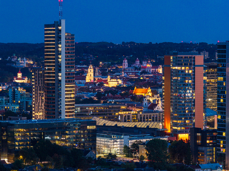 Aerial view of the illuminated Vilnius skyline featuring modern skyscrapers and historic church towers glowing against the blue hour sky in Vilnius Vilnius County Lithuania. Aerial view of the illuminated Vilnius skyline featuring modern skyscrapers and historic church towers glowing against the blue hour sky in Vilnius Vilnius County Lithuania.