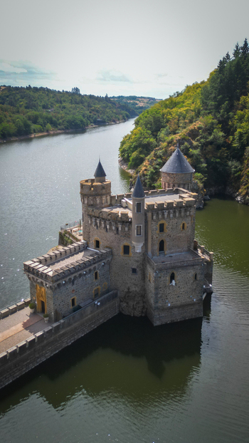 Aerial view of the ancient castle standing firm amidst the flowing river surrounded by lush greenery Saint Priest la Roche Auvergne Rh&ocirc;ne Alpes France.