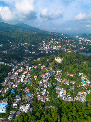 Aerial view of Kandy Lake surrounded by lush green hills dense tropical vegetation and urban buildings in Kandy Central Province Sri Lanka. Aerial view of Kandy Lake surrounded by lush green hills dense tropical vegetation and urban buildings in Kandy Central Province Sri Lanka.