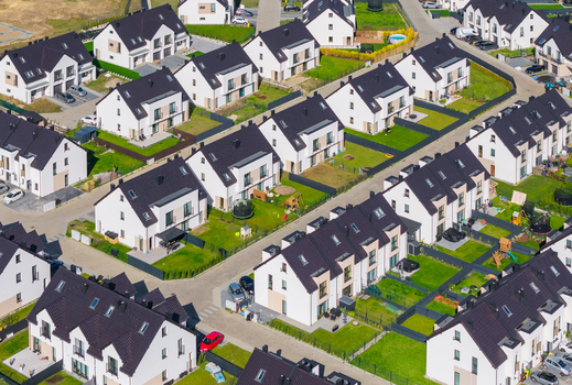 Aerial view of a modern residential neighborhood with rows of white houses featuring dark roofs green lawns and paved streets in Gdansk Pomeranian Voivodeship Poland. Aerial view of a modern residential neighborhood with rows of white houses featuring dark roofs green lawns and paved streets in Gdansk Pomeranian Voivodeship Poland.