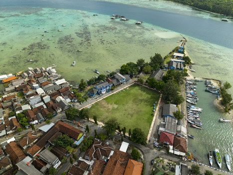 Aerial view of the vibrant town square meeting the turquoise sea where boats bob gently and houses cluster tightly Karimunjawa Central Java Indonesia. Aerial view of the vibrant town square meeting the turquoise sea where boats bob gently and houses cluster tightly Karimunjawa Central Java Indonesia.