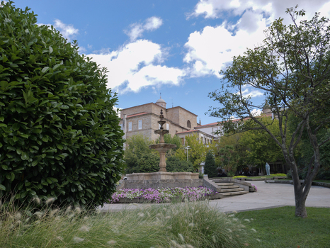 View of the stone fountain in Plaza Obispo Cesareo surrounded by lush greenery flowers and historic buildings in Ourense Province of Ourense Spain. View of the stone fountain in Plaza Obispo Cesareo surrounded by lush greenery flowers and historic buildings in Ourense Province of Ourense Spain.