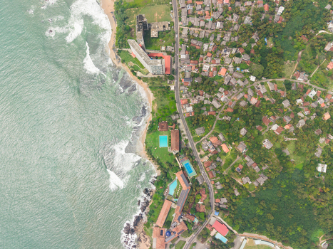 Aerial view of the turquoise coastline with waves crashing on the beach coastal road and lush green residential areas in Galle Southern Province Sri Lanka. Aerial view of the turquoise coastline with waves crashing on the beach coastal road and lush green residential areas in Galle Southern Province Sri Lanka.
