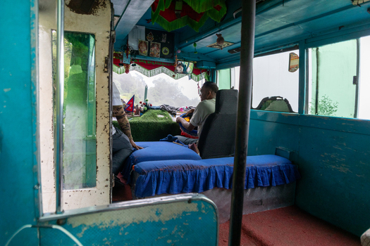 Pokhara Nepal 27 August 2026 View of the interior of a bus traveling through the misty mountain landscape near the Mardi Himal Trek featuring blue seats and curtains.