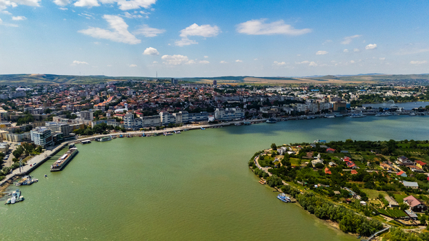 Aerial view of the Danube riverfront featuring the city skyline docked boats and lush greenery along the riverbank in Tulcea Tulcea Romania.