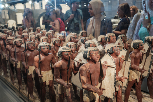 Giza Egypt 16 May 2026 View of the ancient Egyptian wooden soldier figurines from the tomb of Mesehti on display at the Grand Egyptian Museum with visitors in the background.