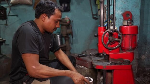 View of a worker operating a red industrial machine Bangladesh.