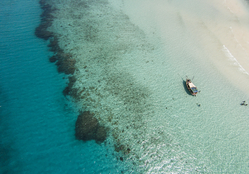 Aerial view of Kisite Mpunguti Marine National Park with turquoise water coral reefs a white sand beach and a small boat with people Kwale Kwale County Kenya. Aerial view of Kisite Mpunguti Marine National Park with turquoise water coral reefs a white sand beach and a small boat with people Kwale Kwale County Kenya.