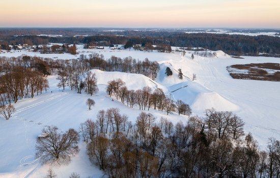 Aerial view of the snow covered hillforts of Kernave surrounded by bare trees and a frozen winter landscape during sunset Kernave Vilnius County Lithuania.