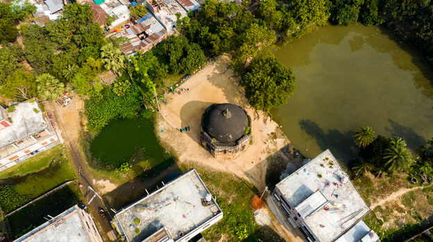 Aerial view of the historic octagonal dome structure surrounded by lush trees ponds and residential buildings in Rohanpur Rajshahi Division Bangladesh.