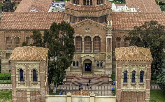 Aerial view of Royce Hall at the UCLA Campus with its red brick facade terracotta roof and students walking on the plaza below in Westwood California United States.