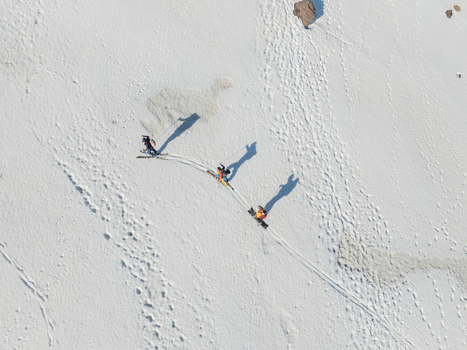 Aerial view of three skiers descending the snow covered south slope of Mount Etna with long shadows and tracks in Nicolosi Sicilia Italy. Aerial view of three skiers descending the snow covered south slope of Mount Etna with long shadows and tracks in Nicolosi Sicilia Italy.