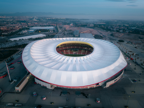 Aerial view of Riyadh Air Metropolitano Stadium with its distinctive white roof and circular design surrounded by urban infrastructure and parking areas. Madrid Comunidad de Madrid Spain.