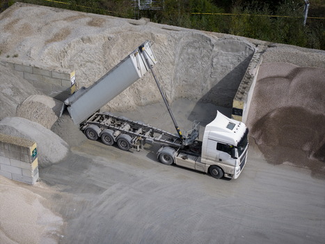 Aerial view of a white dump truck unloading gravel at an industrial asphalt plant facility in Krakow Lesser Poland Voivode Poland.