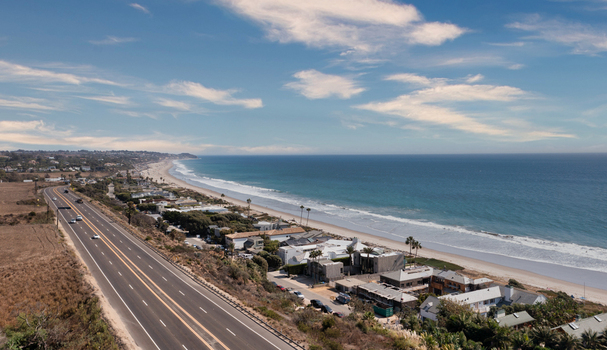 Aerial view of the Pacific Coast Highway running alongside the sandy beach and residential properties in Malibu California United States.