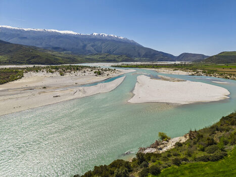 Aerial view of Vjosa Wild River National Park with turquoise river waters gravel riverbeds and snow capped mountains in Permet Gjirokaster County Albania. Aerial view of Vjosa Wild River National Park with turquoise river waters gravel riverbeds and snow capped mountains in Permet Gjirokaster County Albania.