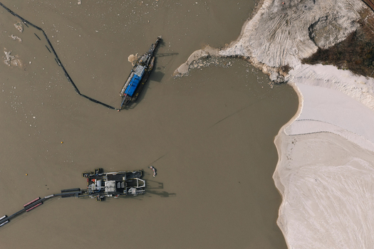 Aerial view of industrial dredging equipment operating in a murky water basin with sandy banks and sediment deposits in Dulmen North Rhine Westphalia Germany. Aerial view of industrial dredging equipment operating in a murky water basin with sandy banks and sediment deposits in Dulmen North Rhine Westphalia Germany.