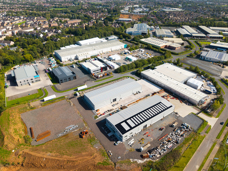 Aerial view of an industrial park featuring modern warehouses with solar panels paved parking areas and a construction site in Lisburn Northern Ireland United Kingdom. Aerial view of an industrial park featuring modern warehouses with solar panels paved parking areas and a construction site in Lisburn Northern Ireland United Kingdom.