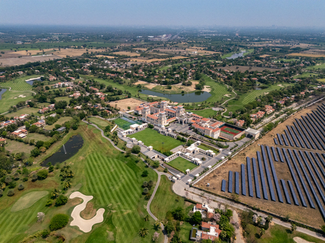 Ahmedabad India 21 March 2026 Aerial view of Kalhaar Blues Greens Golf Club featuring green fairways water hazards and the clubhouse complex adjacent to a solar panel field.