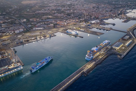 Civitavecchia Italy 23 August 2026 Aerial view of Civitavecchia Port with cruise ships docked at the pier a ferry navigating the harbor and the surrounding coastal town infrastructure under soft morning light.