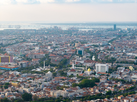 Surabaya East Java Indonesia 28 August 2026 Aerial view of the dense urban landscape featuring rooftops mosques with golden domes and a bustling harbor.