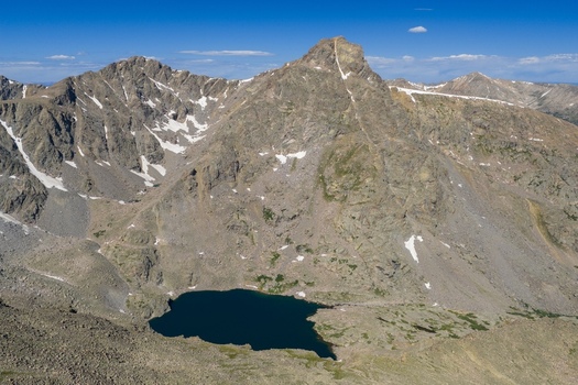 Aerial view of Mount of the Holy Cross in the Sawatch Range featuring a deep blue alpine lake rugged rocky slopes and patches of snow under a clear sky in Vail Colorado United States. Aerial view of Mount of the Holy Cross in the Sawatch Range featuring a deep blue alpine lake rugged rocky slopes and patches of snow under a clear sky in Vail Colorado United States.