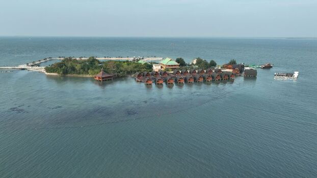 Aerial view of Pulau Lima Resort featuring traditional wooden bungalows over the water lush tropical vegetation and clear blue sea in Kasemen Banten Indonesia. Aerial view of Pulau Lima Resort featuring traditional wooden bungalows over the water lush tropical vegetation and clear blue sea in Kasemen Banten Indonesia.