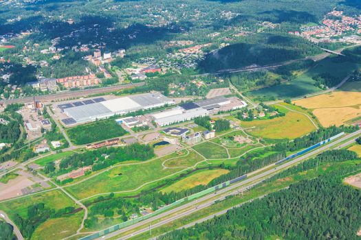 View of industrial warehouses surrounded by green fields and forest Helsinki Uusimaa Finland.