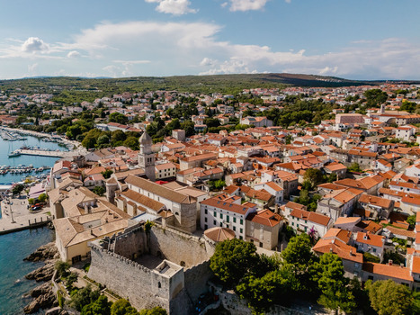 Aerial view of the historic town of Krk featuring the cathedral Frankopan Castle and red tiled rooftops overlooking the harbor in Krk Primorje Gorski Kotar Croatia.