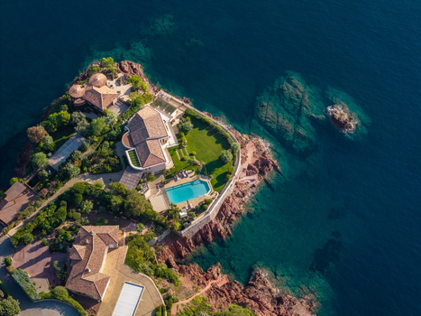 Aerial view of Le Trayas featuring luxury villas with swimming pools nestled on red rock cliffs overlooking the Mediterranean Sea in Saint Raphael Provence Alpes Cote d Azur France. Aerial view of Le Trayas featuring luxury villas with swimming pools nestled on red rock cliffs overlooking the Mediterranean Sea in Saint Raphael Provence Alpes Cote d Azur France.