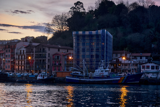Pasai Donibane Spain 09 March 2026 View of the main harbor street with fishing boats moored at the dock and traditional buildings under a twilight sky.