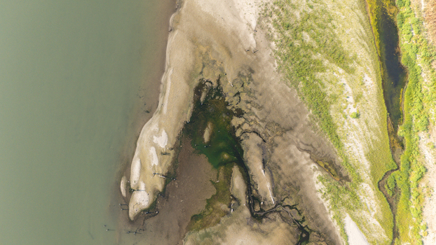 Aerial view of Po River with low water levels caused by drought and summer heatwave exposing sediments sandy beaches and dry riverbed in Castelvetro Piacentino Emilia Romagna Italy. Aerial view of Po River with low water levels caused by drought and summer heatwave exposing sediments sandy beaches and dry riverbed in Castelvetro Piacentino Emilia Romagna Italy.