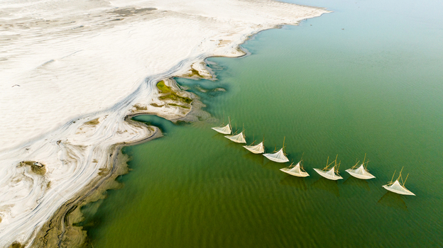 Aerial view of traditional fishing nets set in the calm green waters of the Padma River near the sandy banks of Pabna Rajshahi Division Bangladesh.