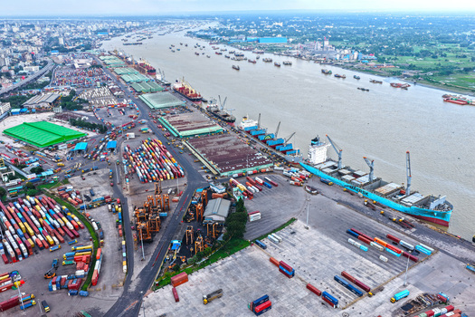 Aerial view of Chattogram Port with cargo ships docked at the quay rows of colorful shipping containers industrial cranes and the Karnaphuli River in Chittagong Chittagong Division Bangladesh.