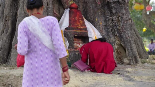 View of a woman praying at a sacred shrine in Lumbini Nepal.