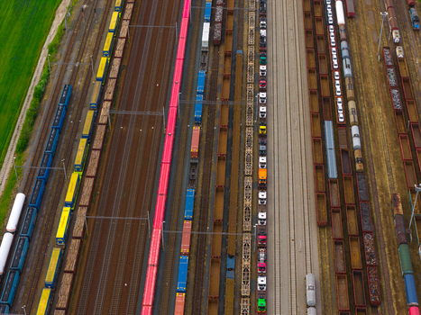 Aerial view of a busy freight train yard with numerous colorful cargo cars parked on parallel tracks next to a green field in Breclav South Moravian Region Czechia.