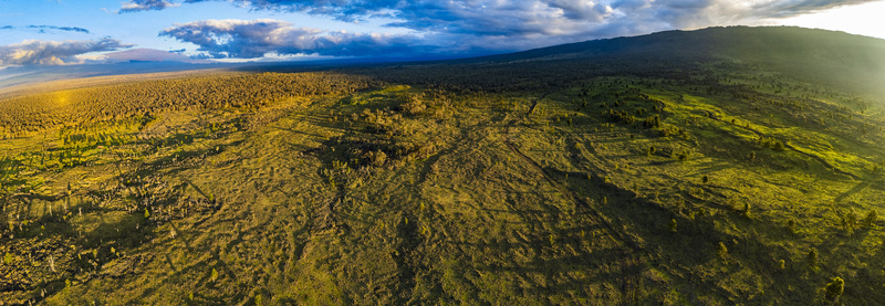 Aerial view of the Puu Waawaa cinder cone surrounded by lush green vegetation and ancient lava flows under a dramatic sunset sky Hawaii County Hawaii United States. Aerial view of the Puu Waawaa cinder cone surrounded by lush green vegetation and ancient lava flows under a dramatic sunset sky Hawaii County Hawaii United States.