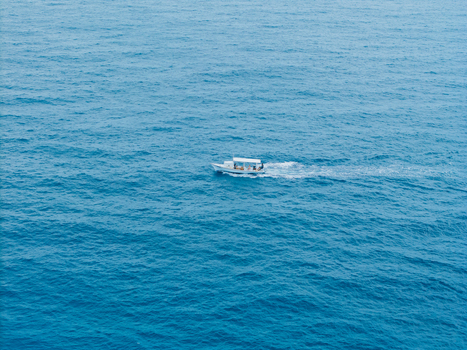 Aerial view of a boat cutting through the vast expanse of turquoise waters leaving a trail of white foam in its wake Vashafaru Island Thiladhummathi Atoll Maldives. Aerial view of a boat cutting through the vast expanse of turquoise waters leaving a trail of white foam in its wake Vashafaru Island Thiladhummathi Atoll Maldives.
