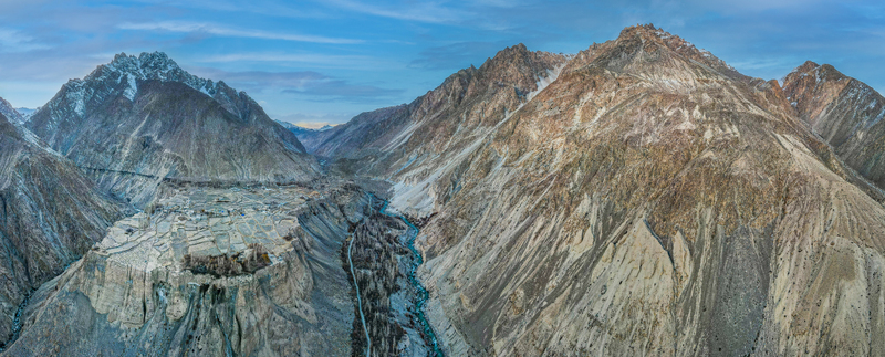 Aerial view of the rugged snow dusted mountains embracing the serene winding river carving through the valley Hunza Nagar Gilgit Pakistan. Aerial view of the rugged snow dusted mountains embracing the serene winding river carving through the valley Hunza Nagar Gilgit Pakistan.