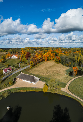 Aerial view of a pond thatched roof building vibrant autumn foliage and a winding road in the Sigulda landscape Sigulda Sigulda Municipality Latvia. Aerial view of a pond thatched roof building vibrant autumn foliage and a winding road in the Sigulda landscape Sigulda Sigulda Municipality Latvia.