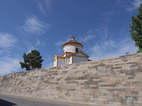 View of the historic Calvary Chapel with its white walls and dome perched atop a large stone retaining wall under a bright blue sky in Portalegre Portalegre Portugal. View of the historic Calvary Chapel with its white walls and dome perched atop a large stone retaining wall under a bright blue sky in Portalegre Portalegre Portugal.