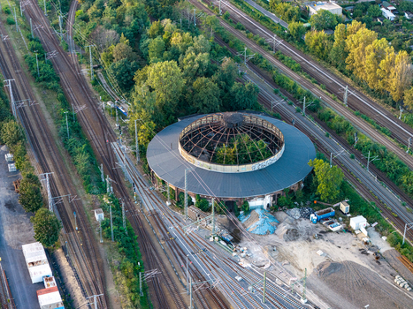 Aerial view of the historic locomotive roundhouse Rummelsburg featuring its circular structure open roof surrounding railway tracks and lush greenery in Berlin Berlin Germany. Aerial view of the historic locomotive roundhouse Rummelsburg featuring its circular structure open roof surrounding railway tracks and lush greenery in Berlin Berlin Germany.