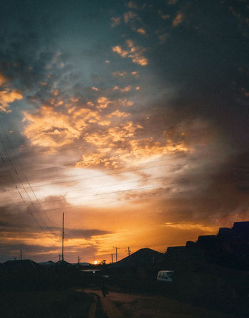 View of a dramatic sunset over residential rooftops with silhouetted power lines in Jos North Plateau Nigeria.