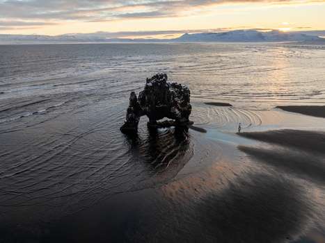 Aerial view of Hvitserkur rock formation on a sandy beach with a person walking nearby during golden hour in Iceland. Aerial view of Hvitserkur rock formation on a sandy beach with a person walking nearby during golden hour in Iceland.