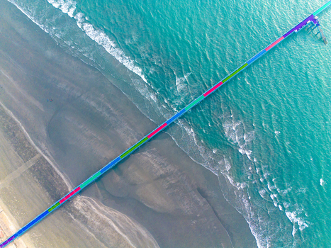 Aerial view of a vibrant pier stretching into the turquoise sea contrasting with the textured sandy beach below Cox s Bazar Chittagong Division Bangladesh.