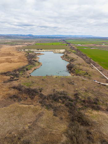 Aerial view of Lake Atanasovsko surrounded by dry reeds and green agricultural fields under a cloudy sky in Burgas Burgas Bulgaria. Aerial view of Lake Atanasovsko surrounded by dry reeds and green agricultural fields under a cloudy sky in Burgas Burgas Bulgaria.